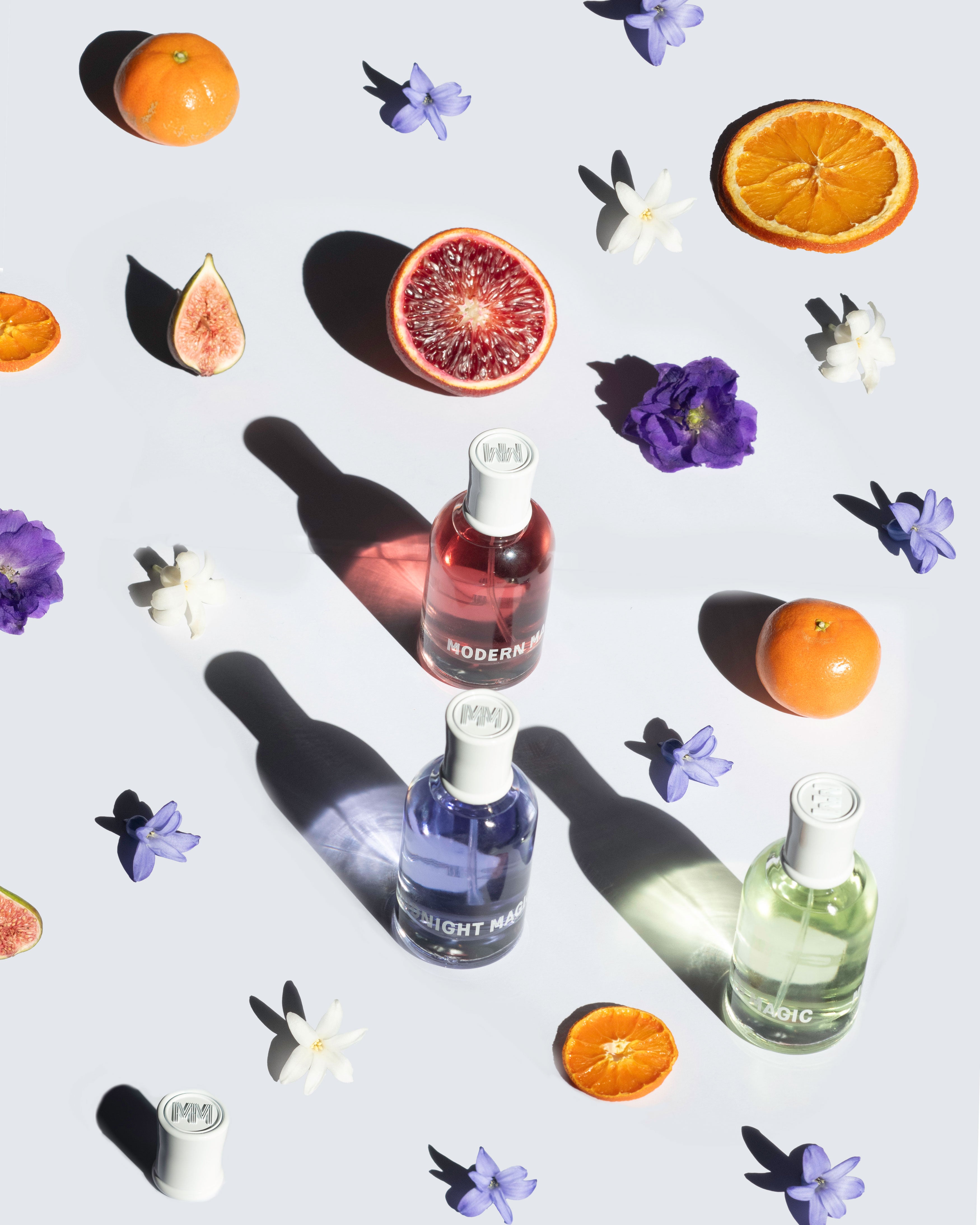 Modern Magic fragrances are displayed alongside flowers and citrus fruits.